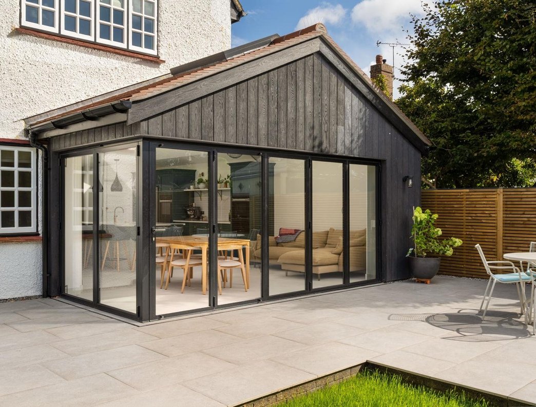 Black timber-clad single-storey extension with bifold doors and patio